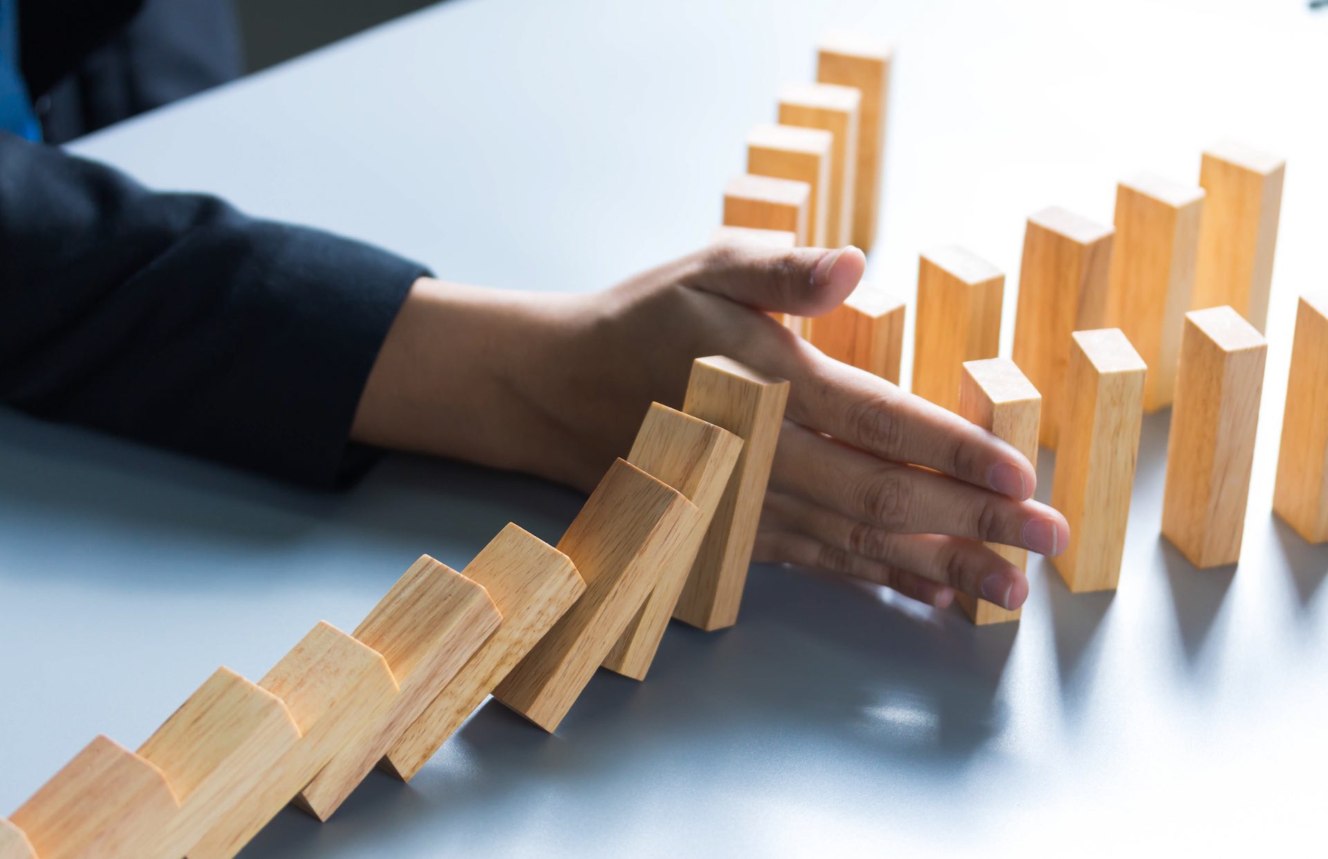 businessman hand stop dominoes continuous toppled or risk with copyspace